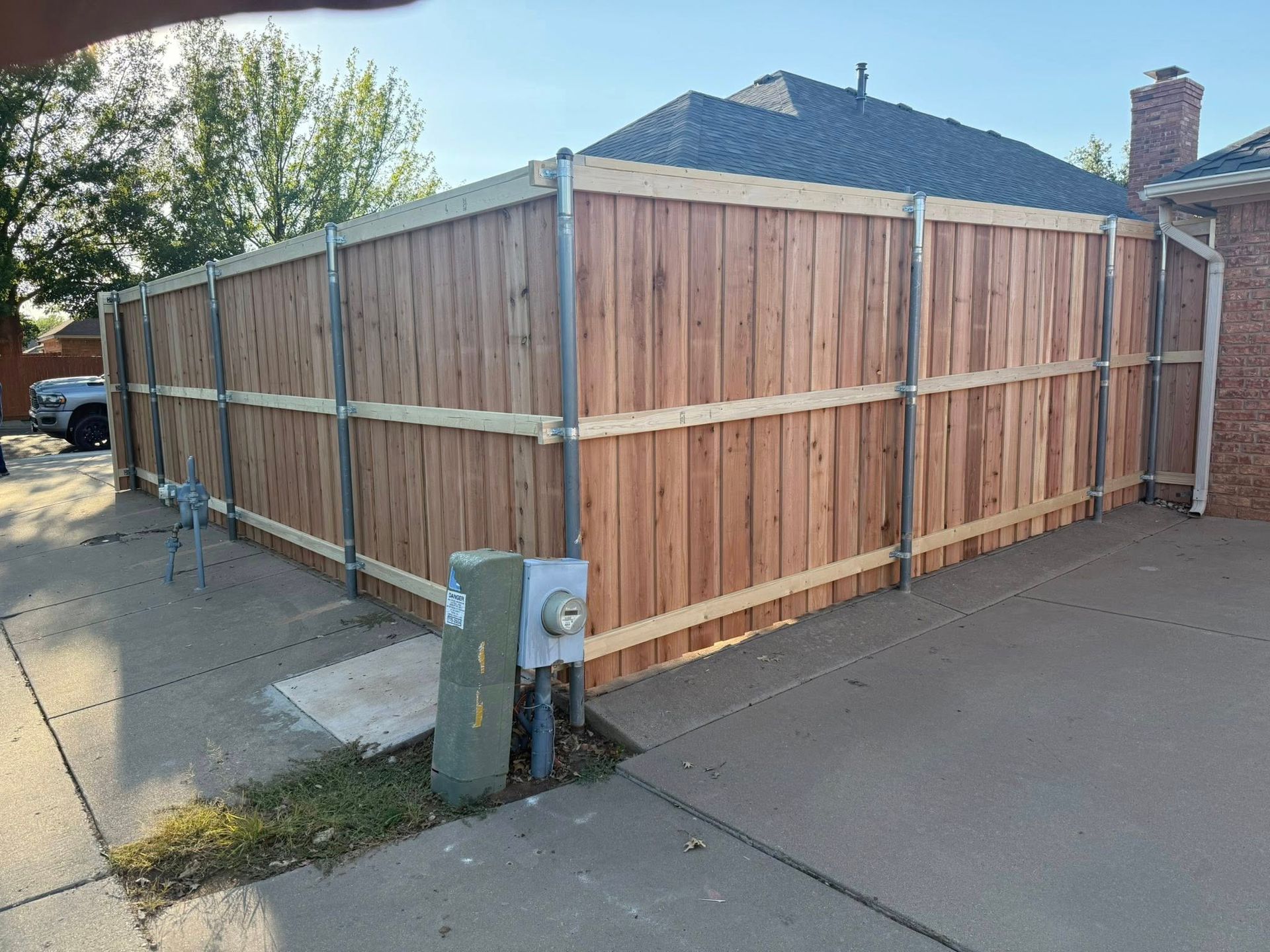 Wooden fence with metal posts in front of a house.