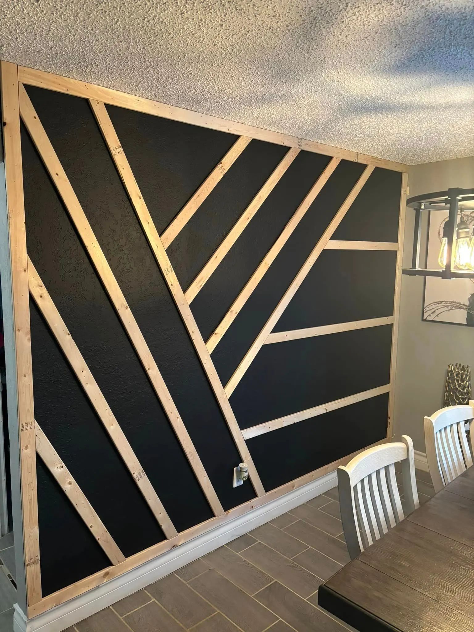 Black accent wall with a geometric wooden frame. The frame is light-colored and the wall has a black textured surface.