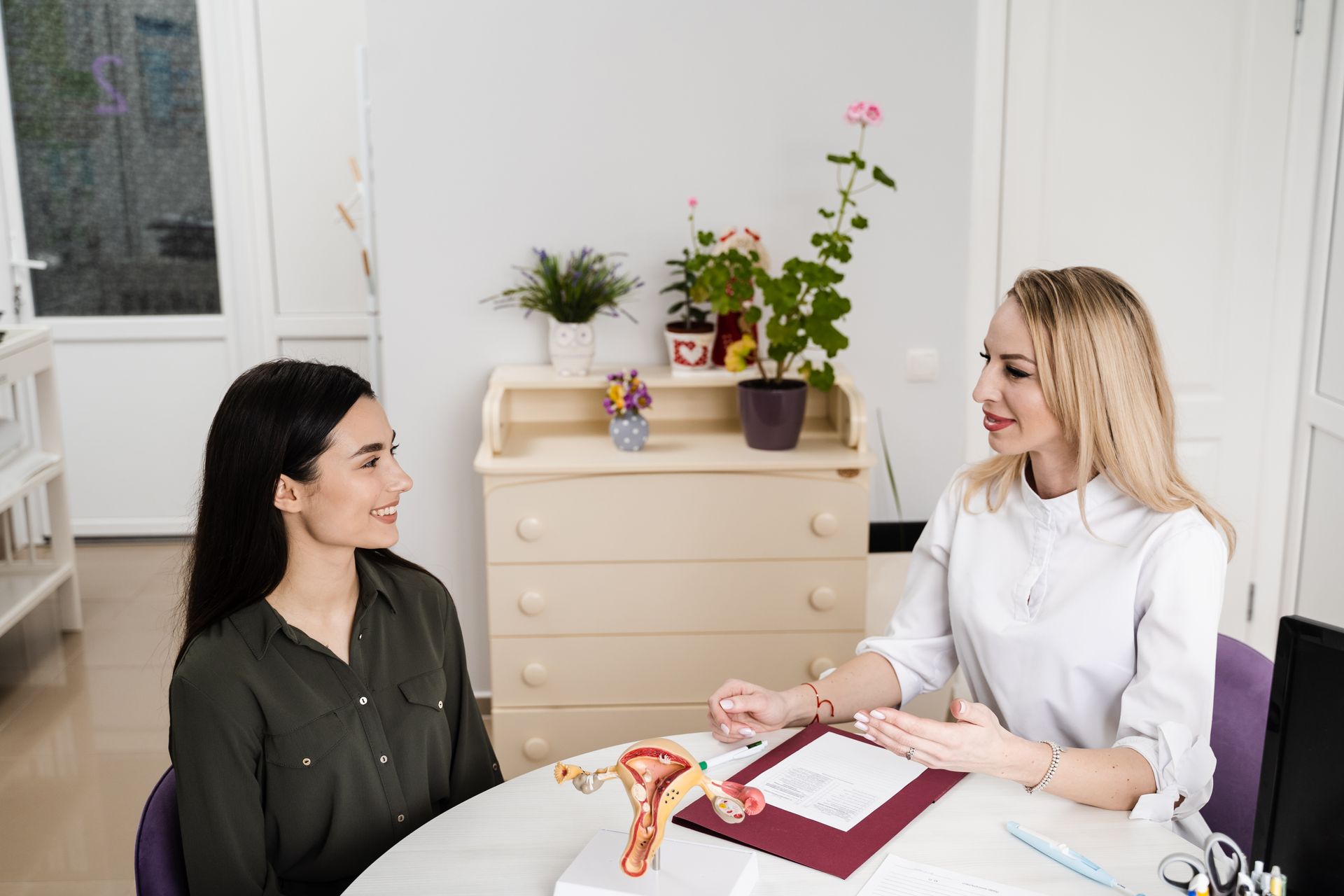 A woman is sitting at a table talking to a doctor.