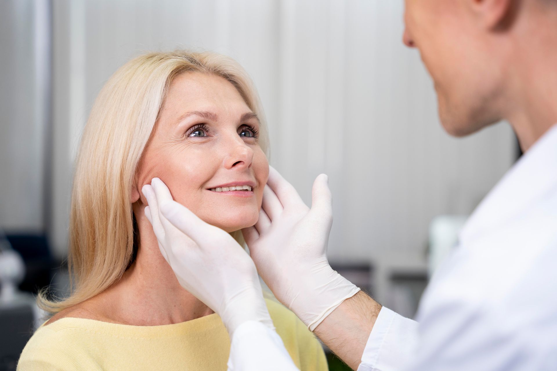 A woman is getting her face examined by a doctor.