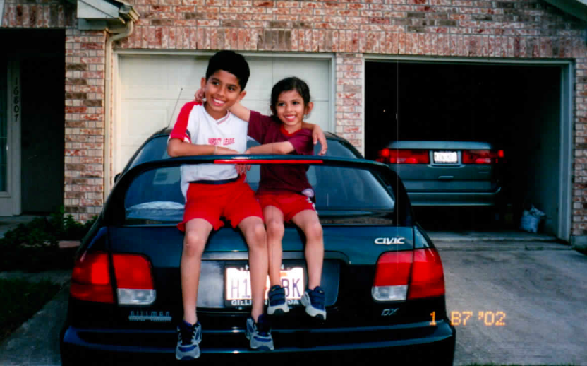 Two children are sitting on the back of a gmc car