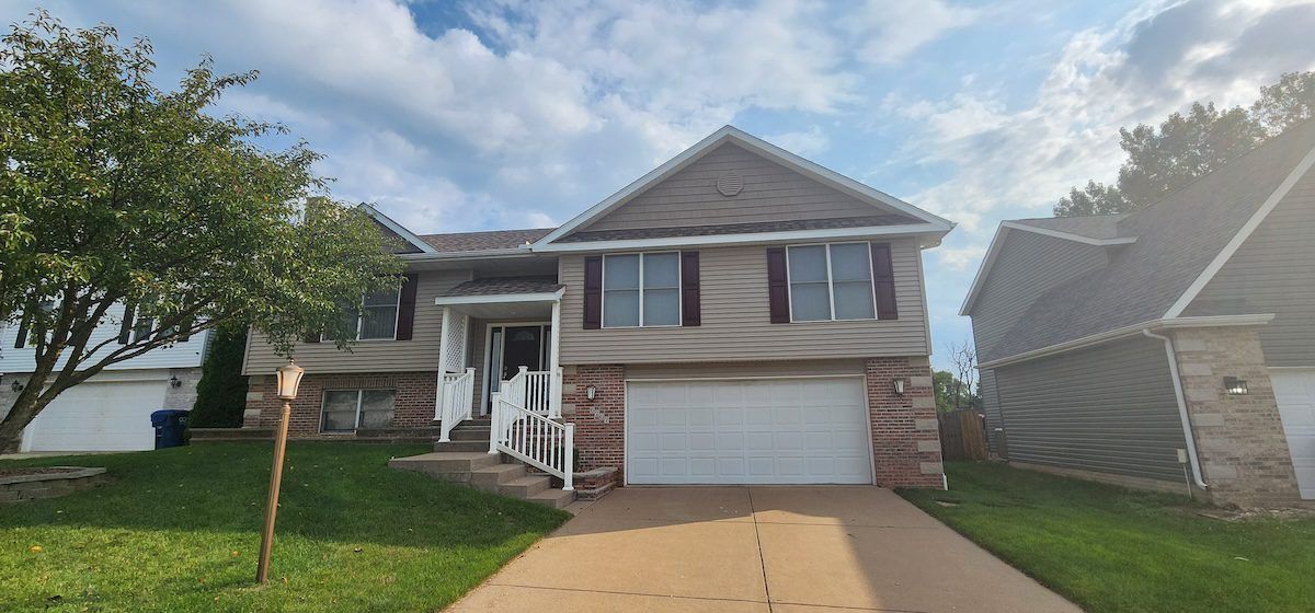 A large brick house with a white garage door is for sale.