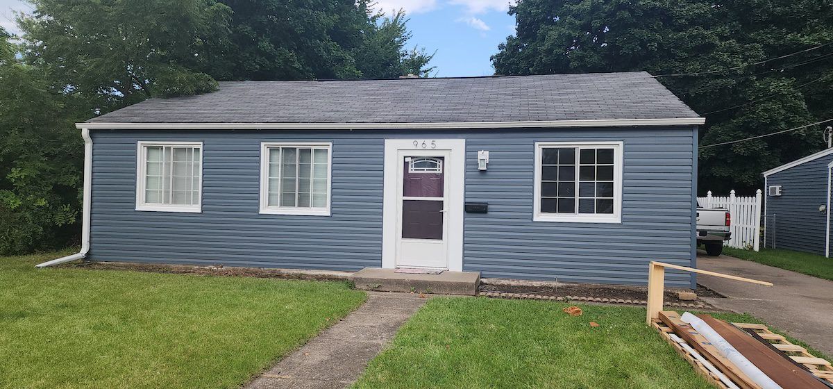 A small blue house with a white door and windows is sitting on top of a lush green lawn.