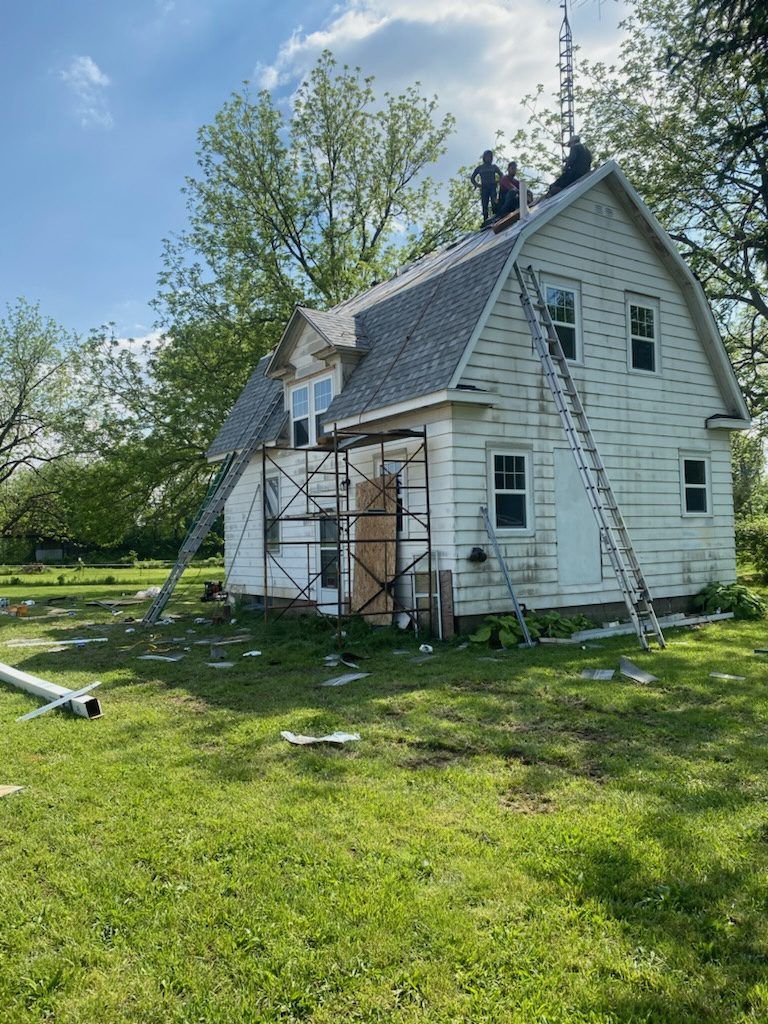 A group of people are working on the roof of a white house.