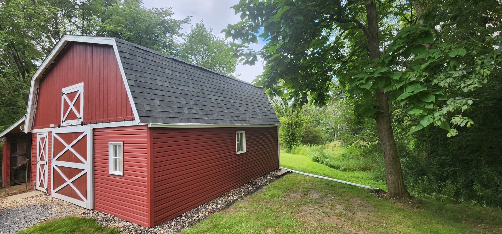 A white house with a gray roof is sitting in the middle of a grassy field.
