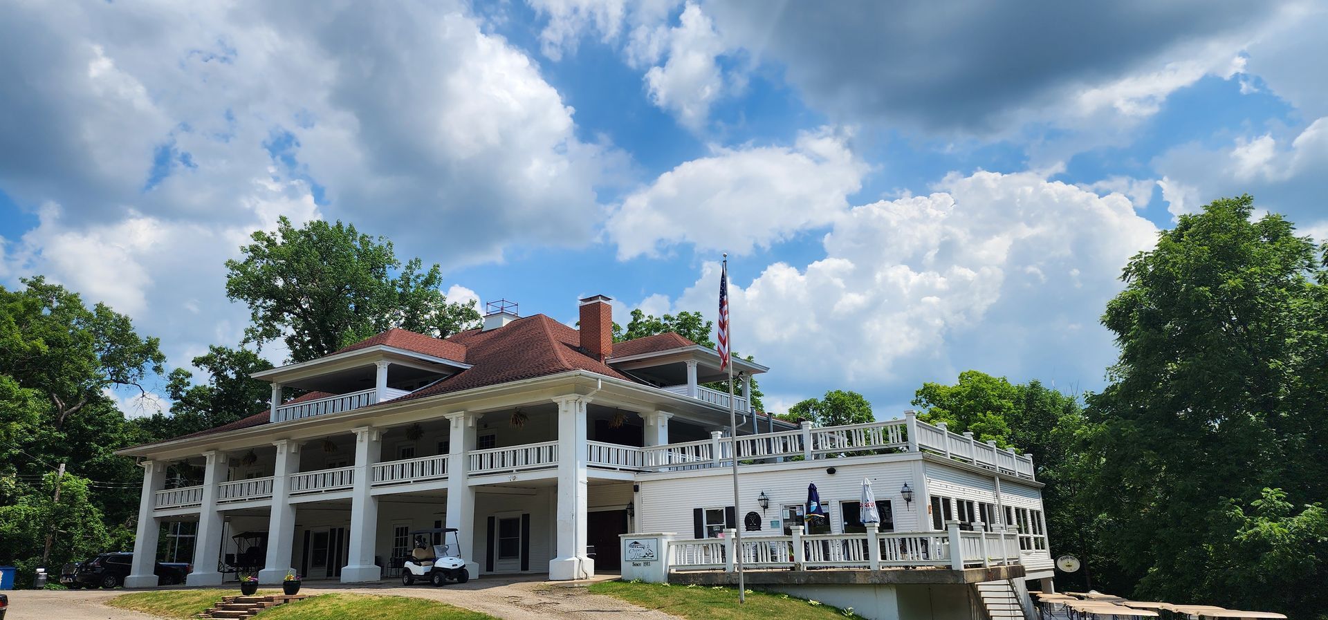 A large white building with columns is surrounded by trees on a cloudy day.