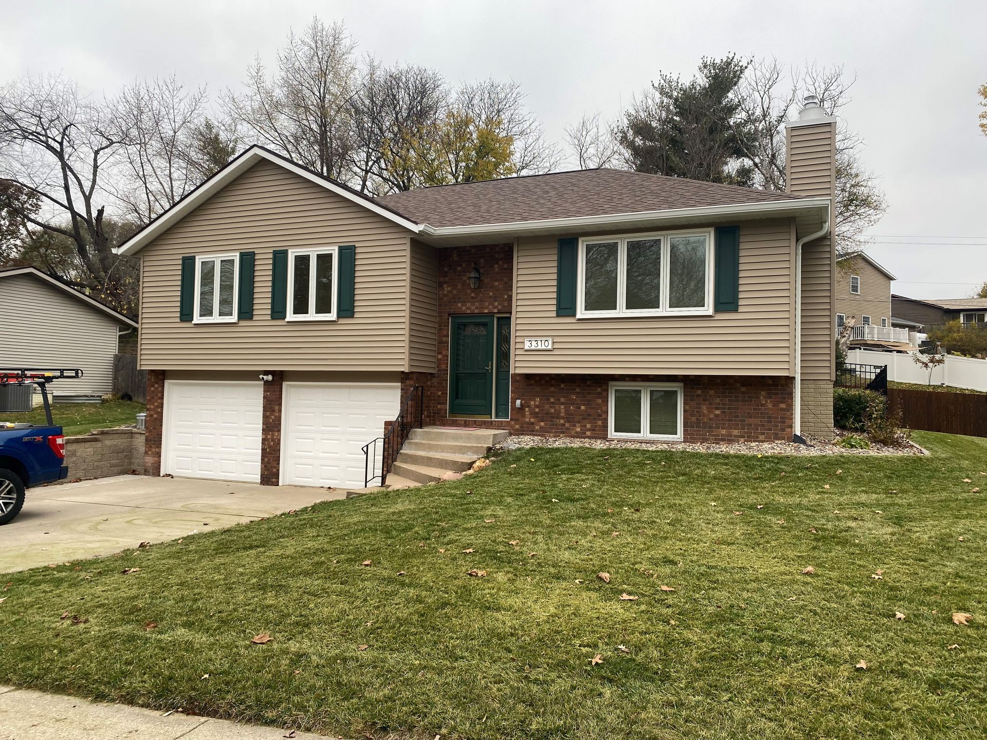 A house with a blue truck parked in front of it.