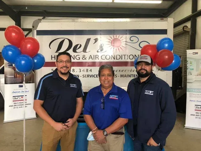 Three people pose in front of a Del's Heating & Air truck with balloons.