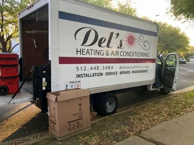 White Del's Heating & Air Conditioning truck parked on a street with its cargo door open, box in front.