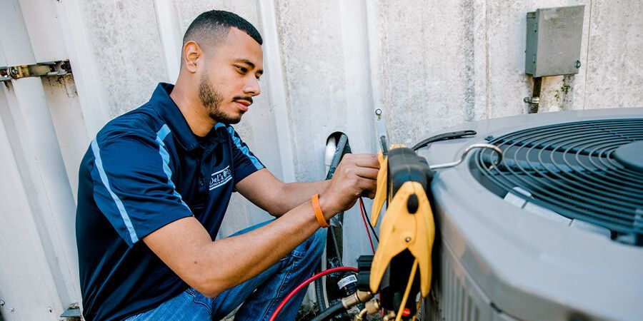 HVAC technician working on an air conditioning unit outside. He's using gauges.
