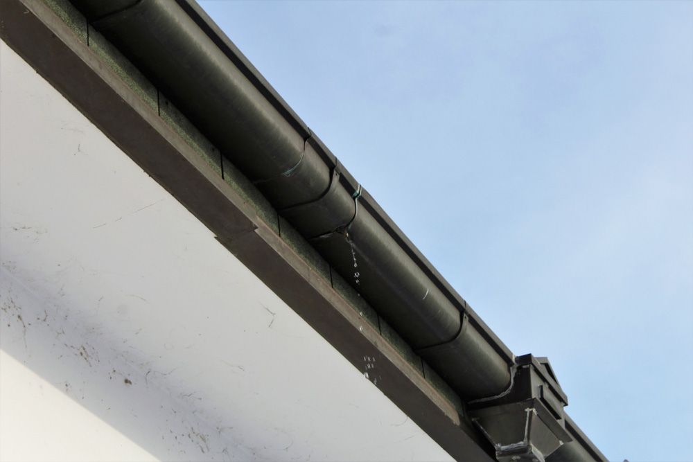 A Gutter on the Side of a Building With Water Coming Out of It — SRV Roofing in Coolum Beach, QLD