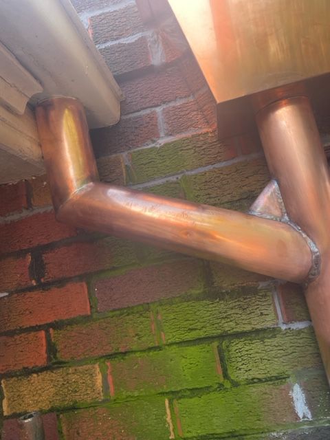 Bronze Pipe Beside A Brick Wall — Expert Roofers in Maroochy River, QLD