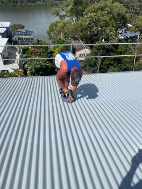 Worker Drilling on Tin Roof — Expert Roofers in Maroochy River, QLD