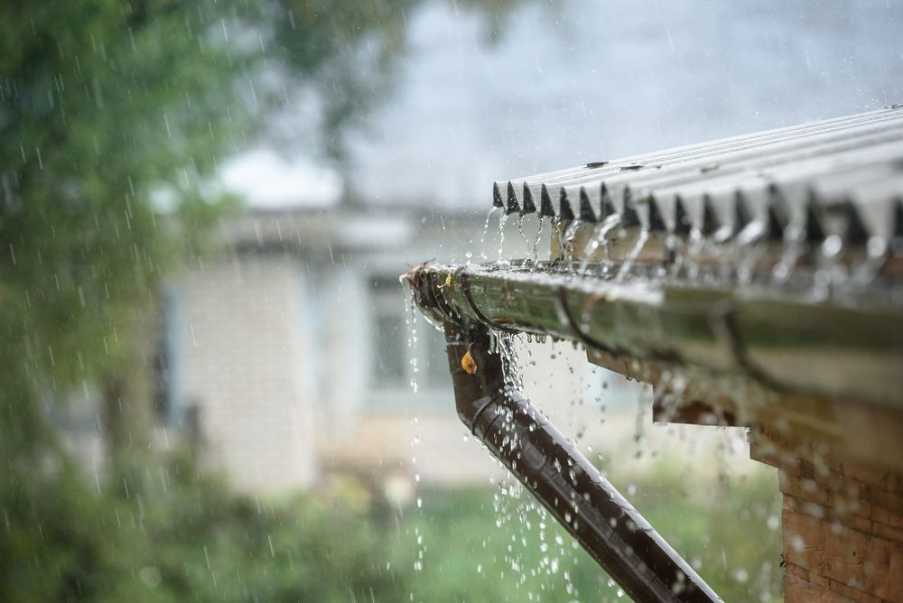 Rainwater Cascades From a Metal Roof Into Gutter