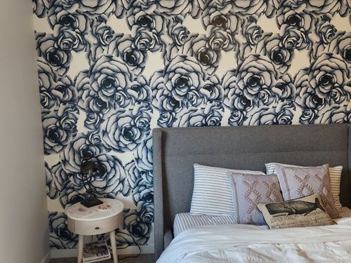 A bedroom with a bed and a nightstand with a floral wallpaper on the wall