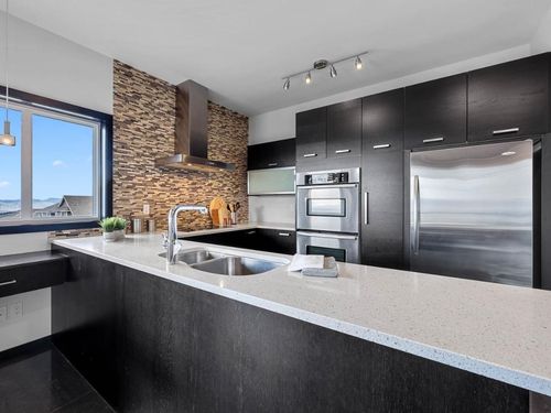 A kitchen with stainless steel appliances , a sink , a refrigerator and a window.