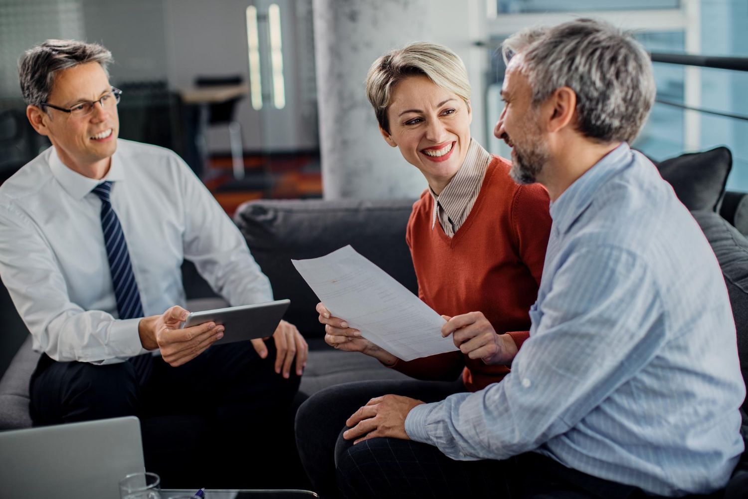 Financial advisor showing paperwork to a smiling couple in an office setting.