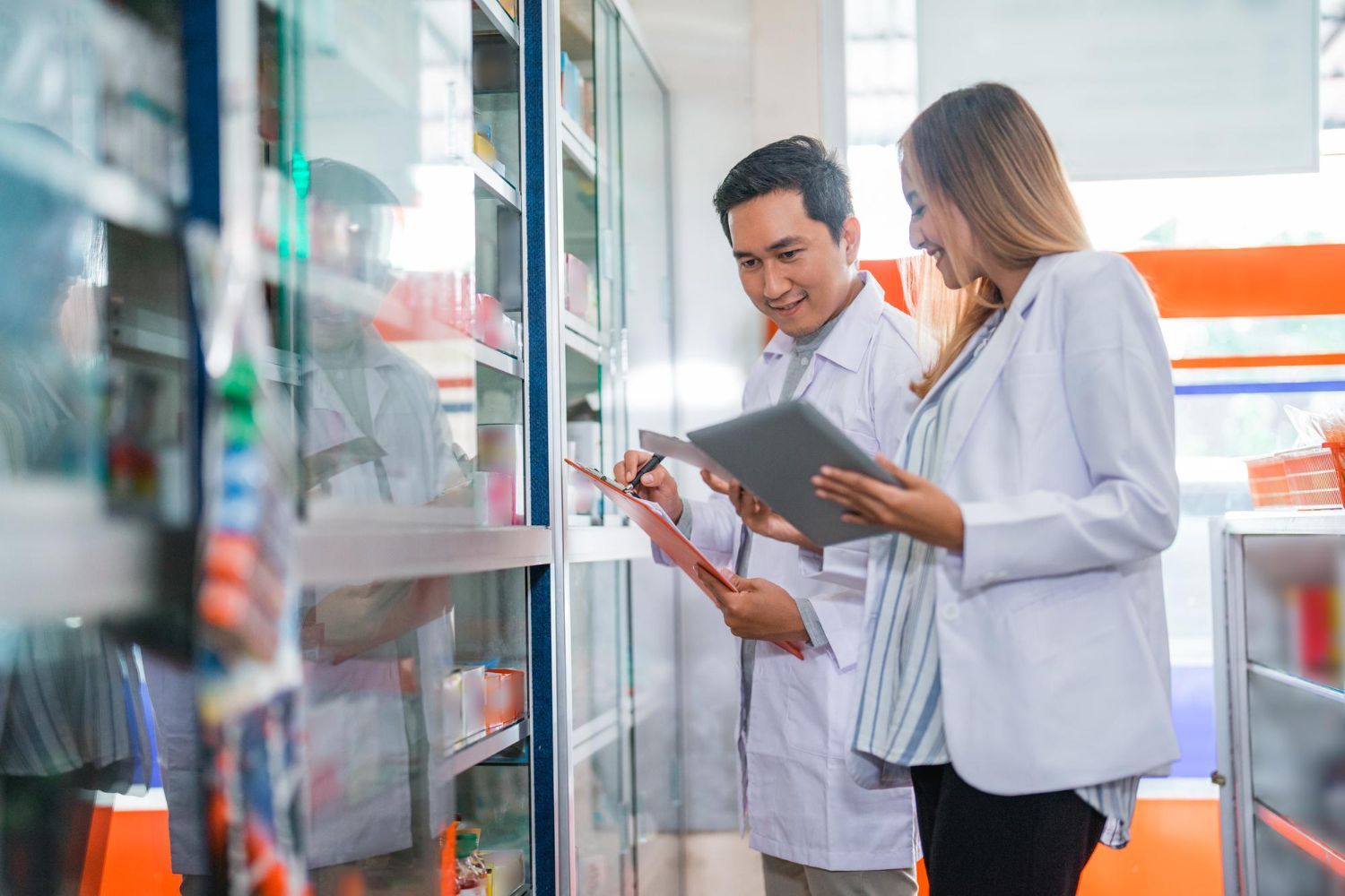 Two people in lab coats reviewing inventory in a pharmacy.