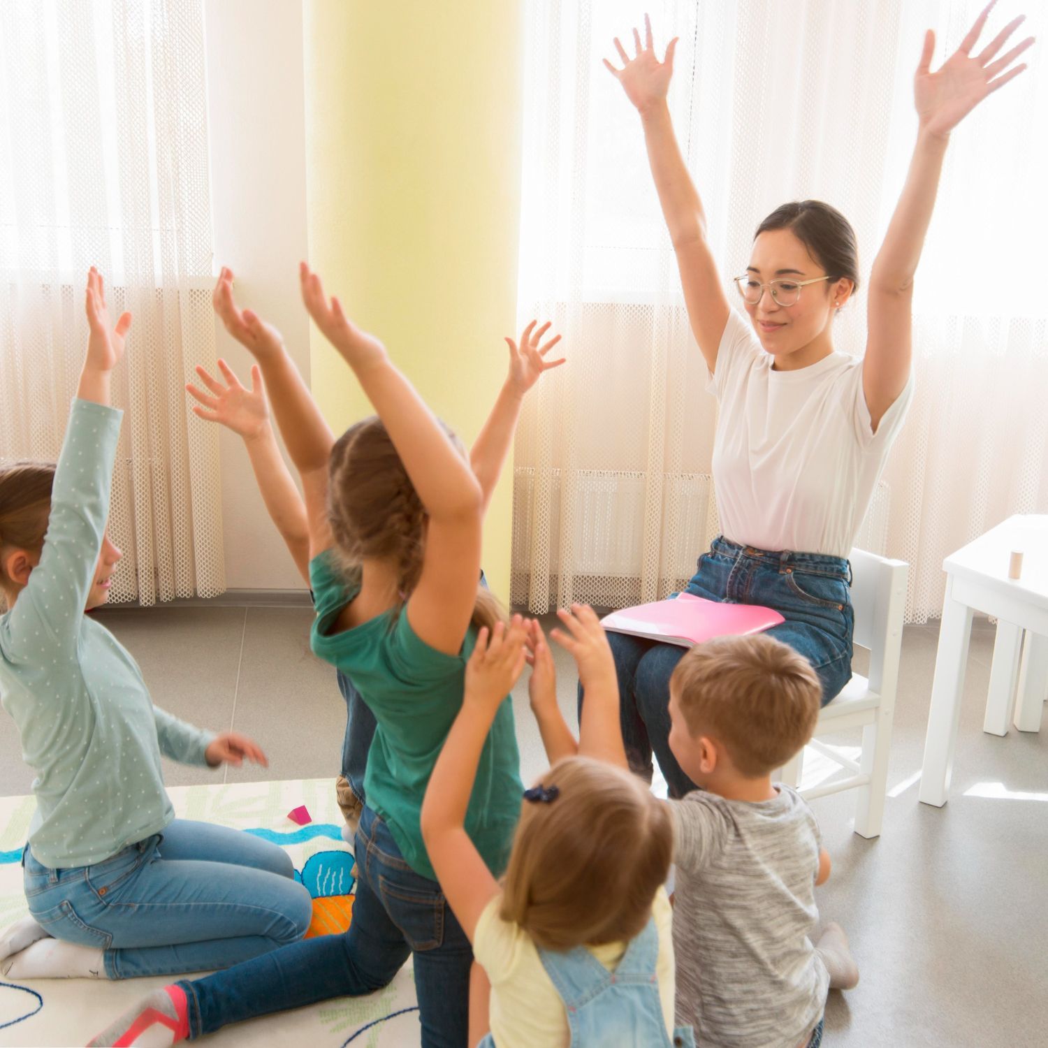 Children and a teacher with arms raised in a brightly lit room.