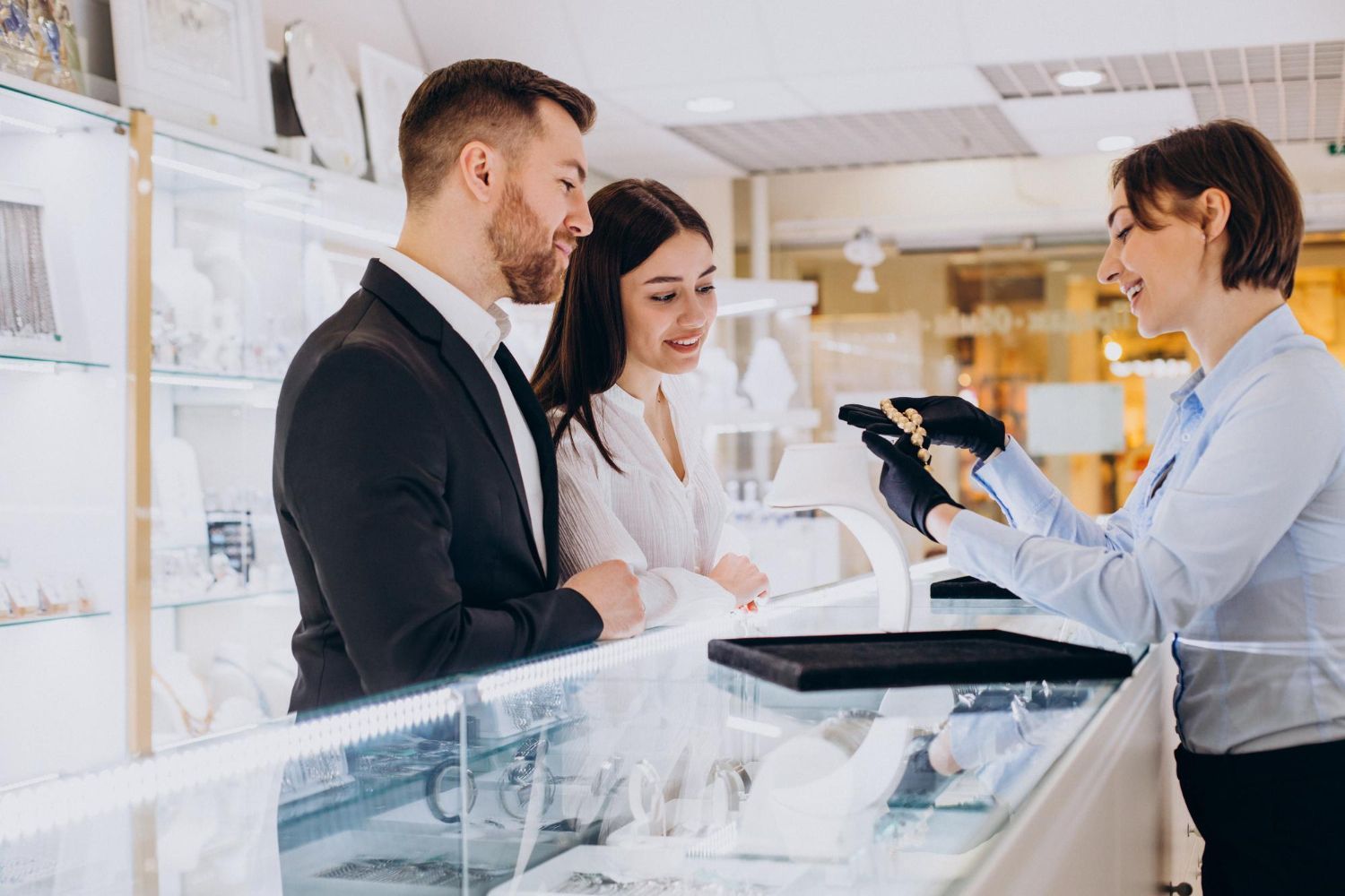 Couple looking at jewelry, a salesperson showing a ring in a display case.