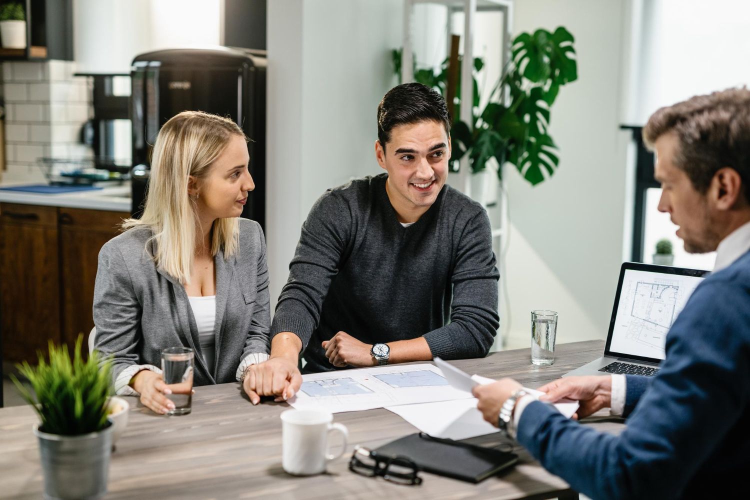 Couple seated at table reviews documents with professional in an office setting.