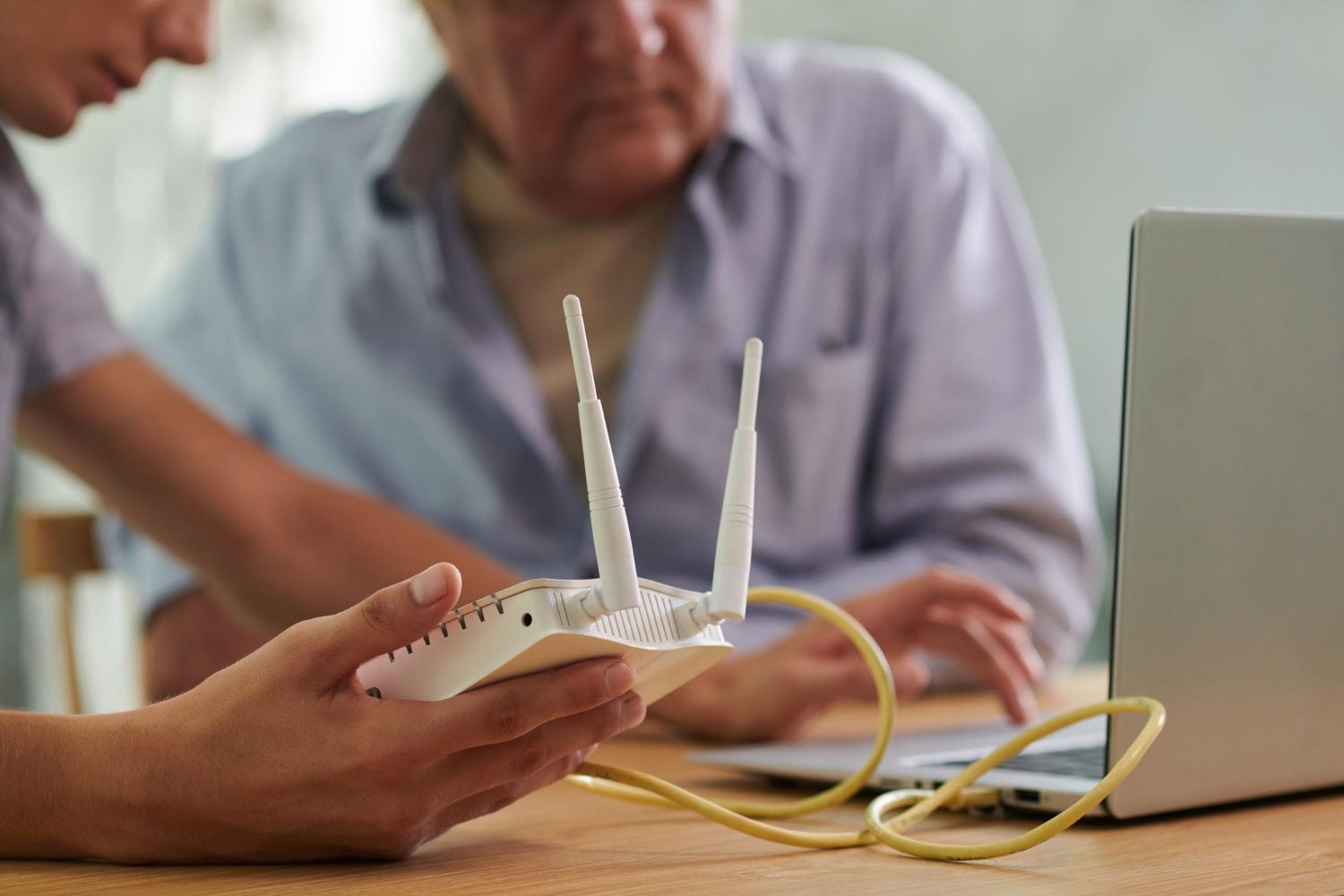 Woman assisting a man with a router connected to a laptop.