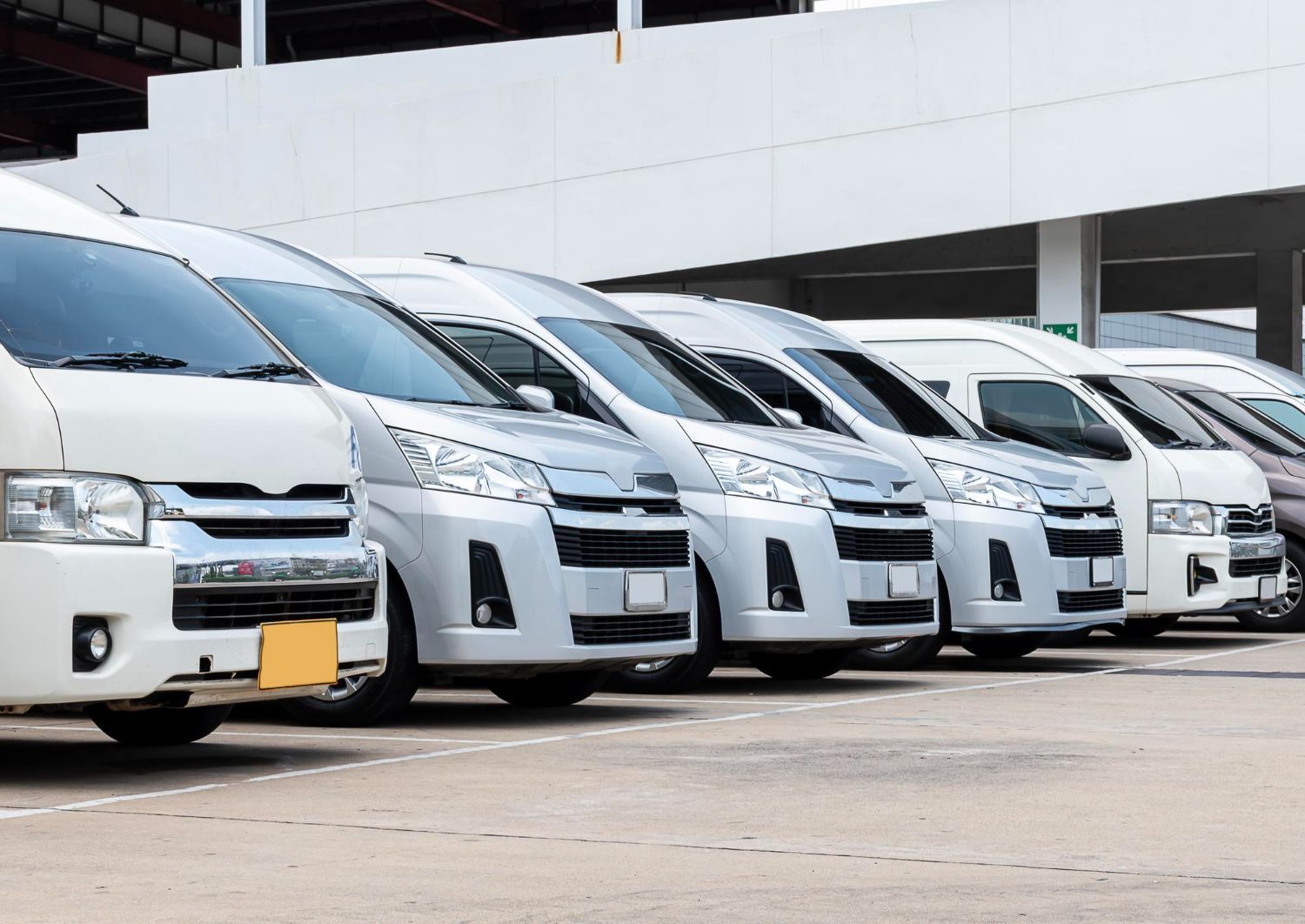 Row of white vans parked in a lot, possibly a rental service.