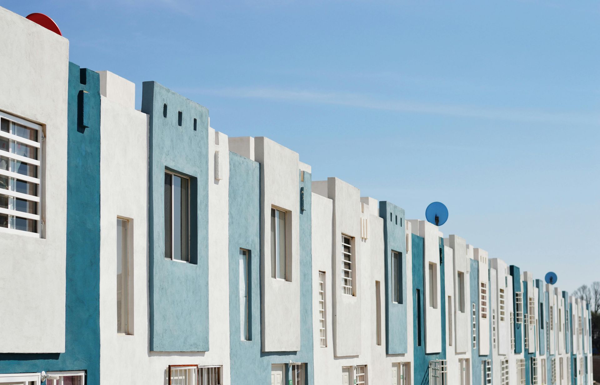 Row of white and teal houses under a clear blue sky.