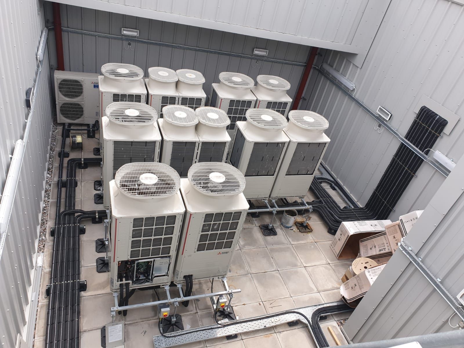 VRF Air conditioning units inside a metal enclosure, with pipes and wiring.