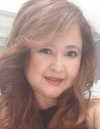 Smiling woman with short gray hair and sunglasses on head, outdoors.