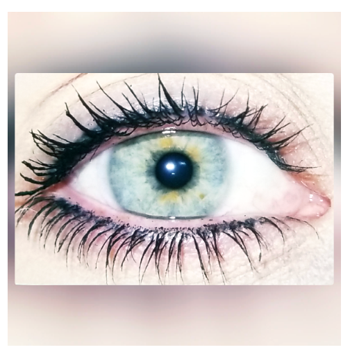Close-up of a light blue eye with dark eyelashes and mascara.