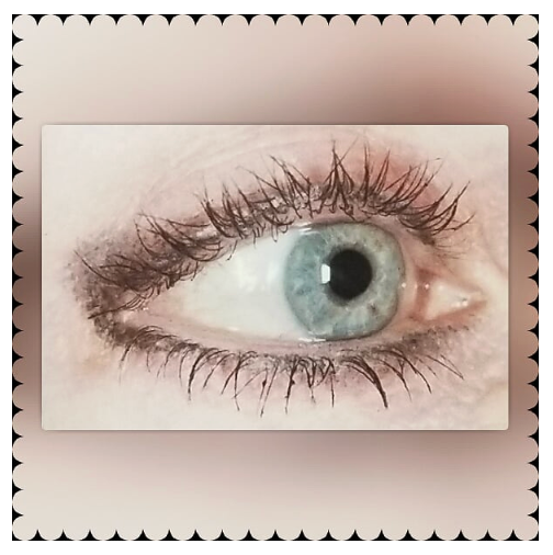 Blue eye with long eyelashes, dark shadow, and white skin.