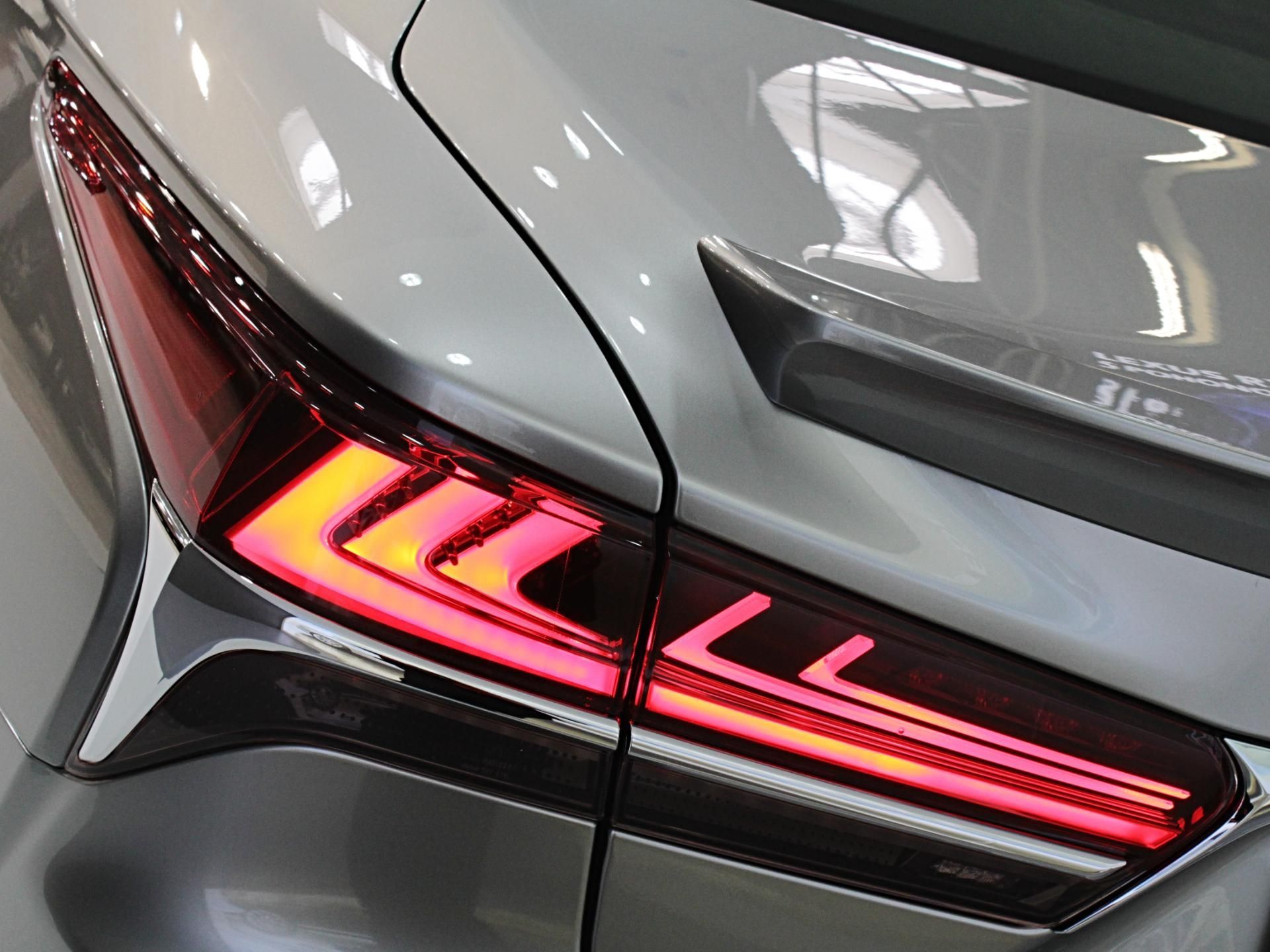 Close-up of a silver car’s rear taillight with red LED strips illuminated