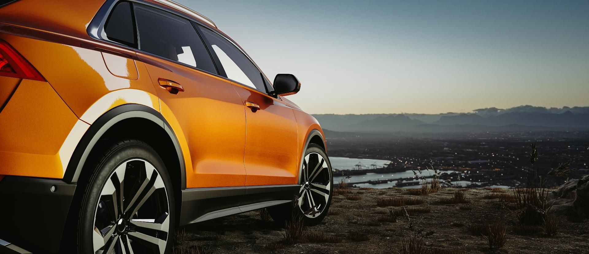 Orange SUV parked on a rocky overlook at sunset, with distant mountains and water in the background