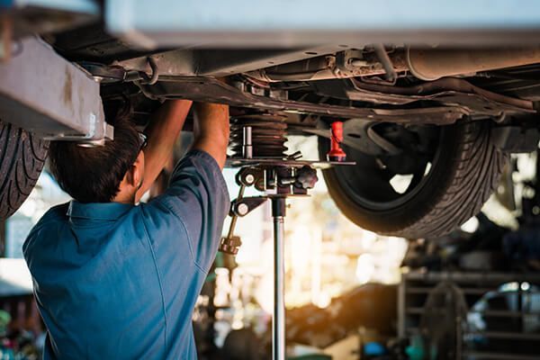 Mechanic working under a car on a lift in a repair shop