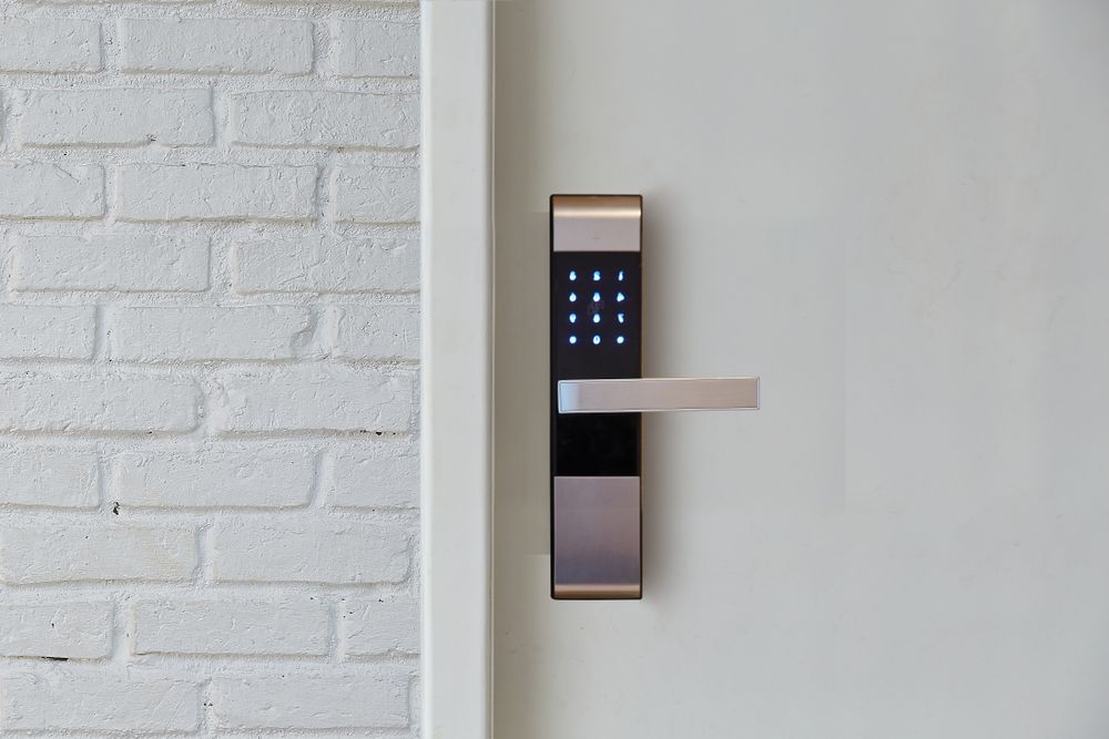 A door with a digital door lock on it and a white brick wall behind it.