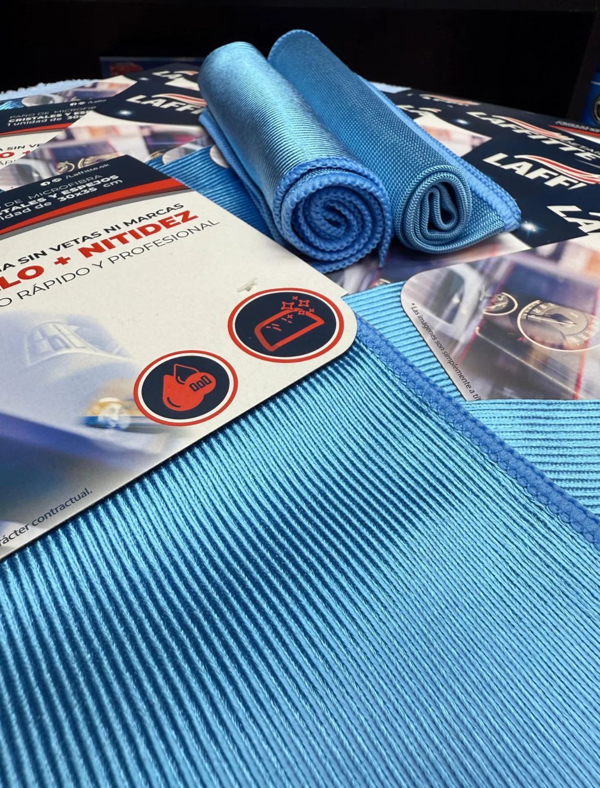 Dos paños de microfibra azules enrollados con paño de limpieza e instrucciones del producto, configuración interior.
