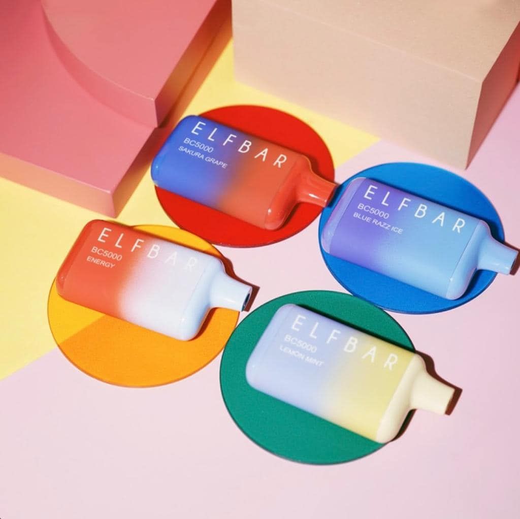 Four Elf Bar disposable vapes on colored circles: blue raspberry, blueberry, strawberry ice, and lemon.