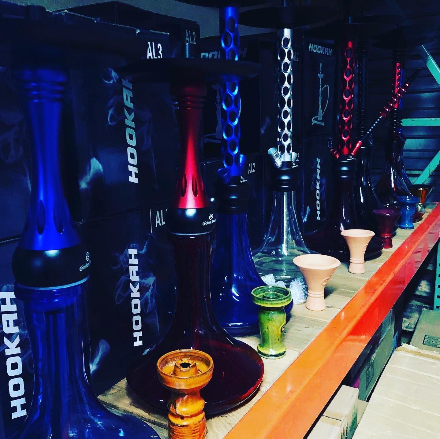 Row of colorful hookahs on a shelf, with various shades of blue, red, and silver.