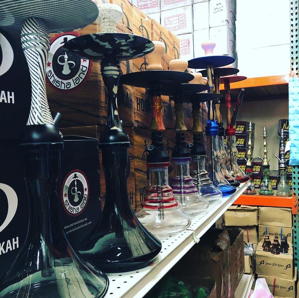 Row of hookahs on a shelf in a store, with various colors and designs.