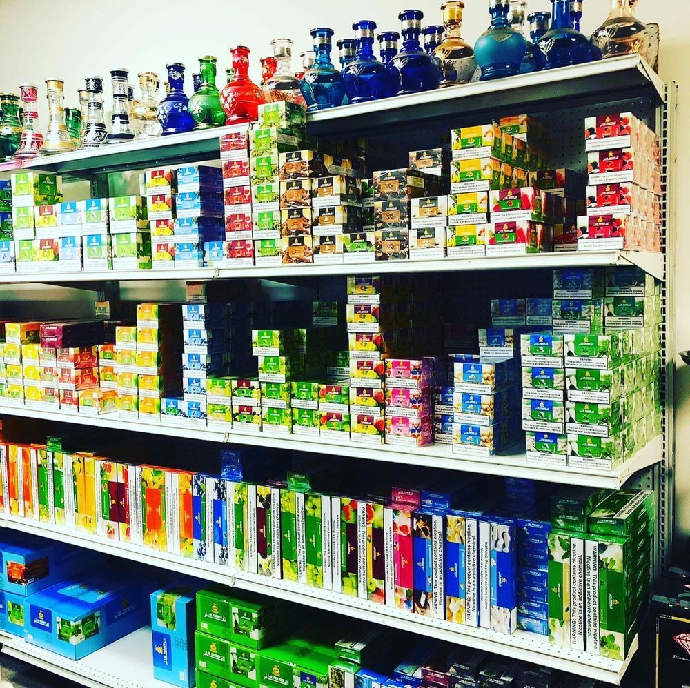 Shelves stocked with colorful hookah tobacco and glass hookahs in a store.