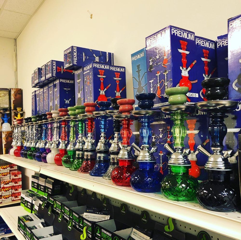Shelves stocked with colorful hookahs in a store setting. Boxes of hookahs are also stacked above.