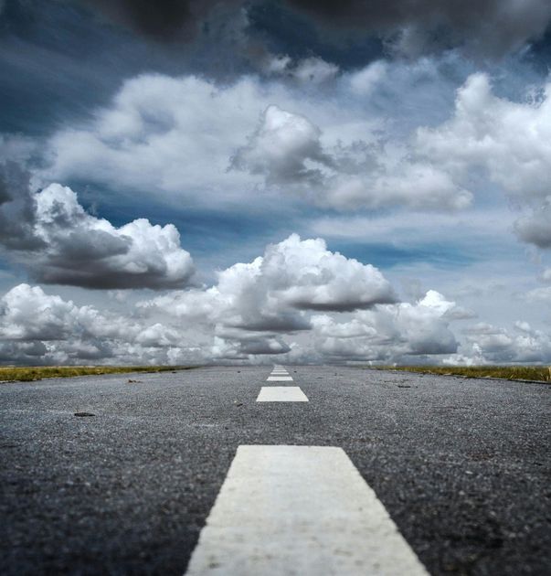 An empty road with a cloudy sky in the background