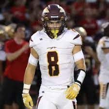 Football player in white uniform with maroon and gold accents; number 8 on chest; helmet with gold face mask.