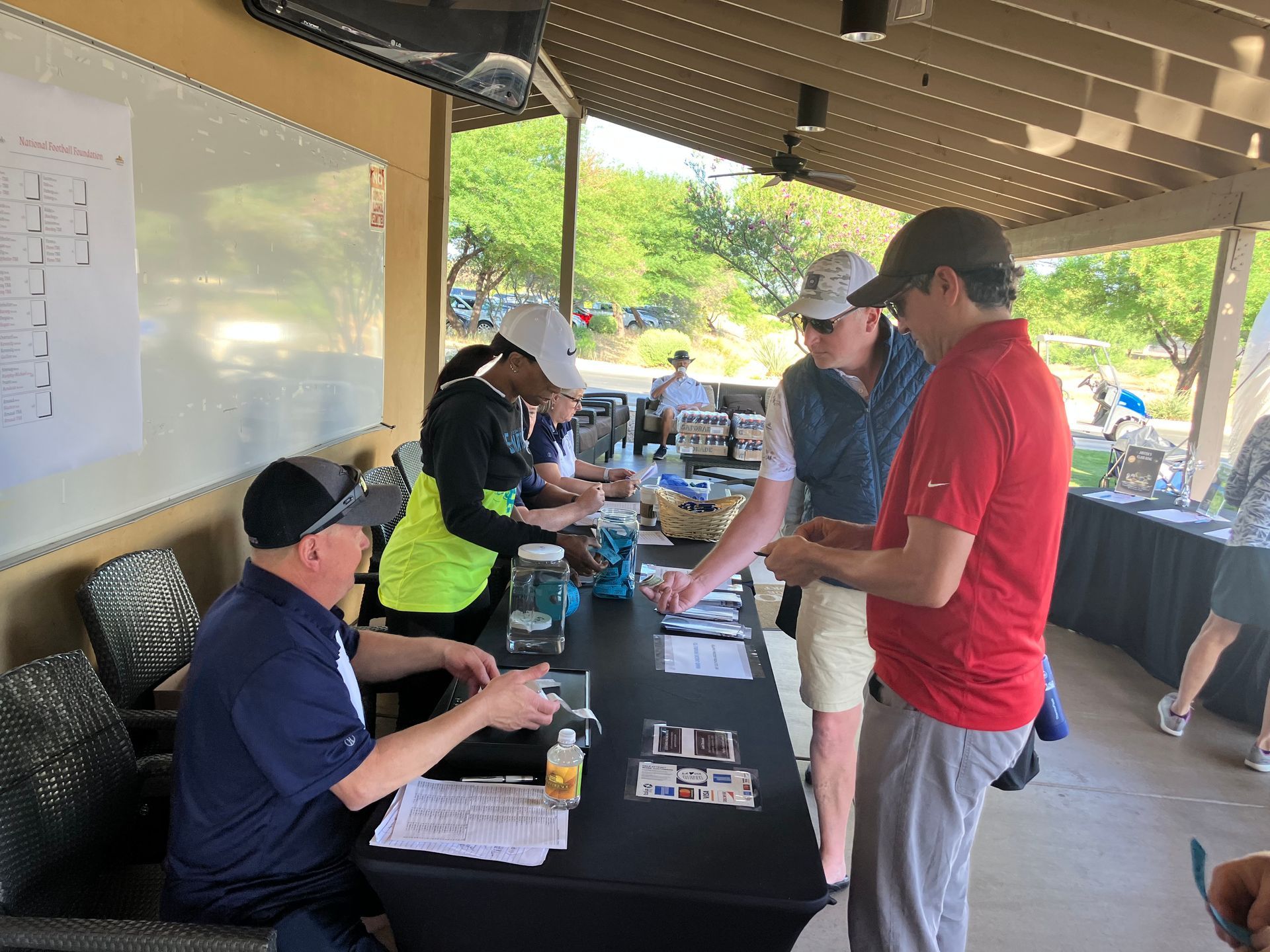 People registering at an outdoor golf event with tables and signage. NFFSAC Fundraiser.