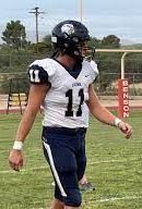 Football player in white jersey with navy sleeves and pants, number 12.