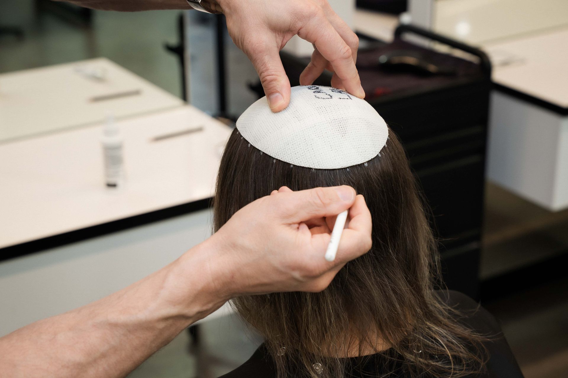 A person having their head measured for a hairpiece in a salon.