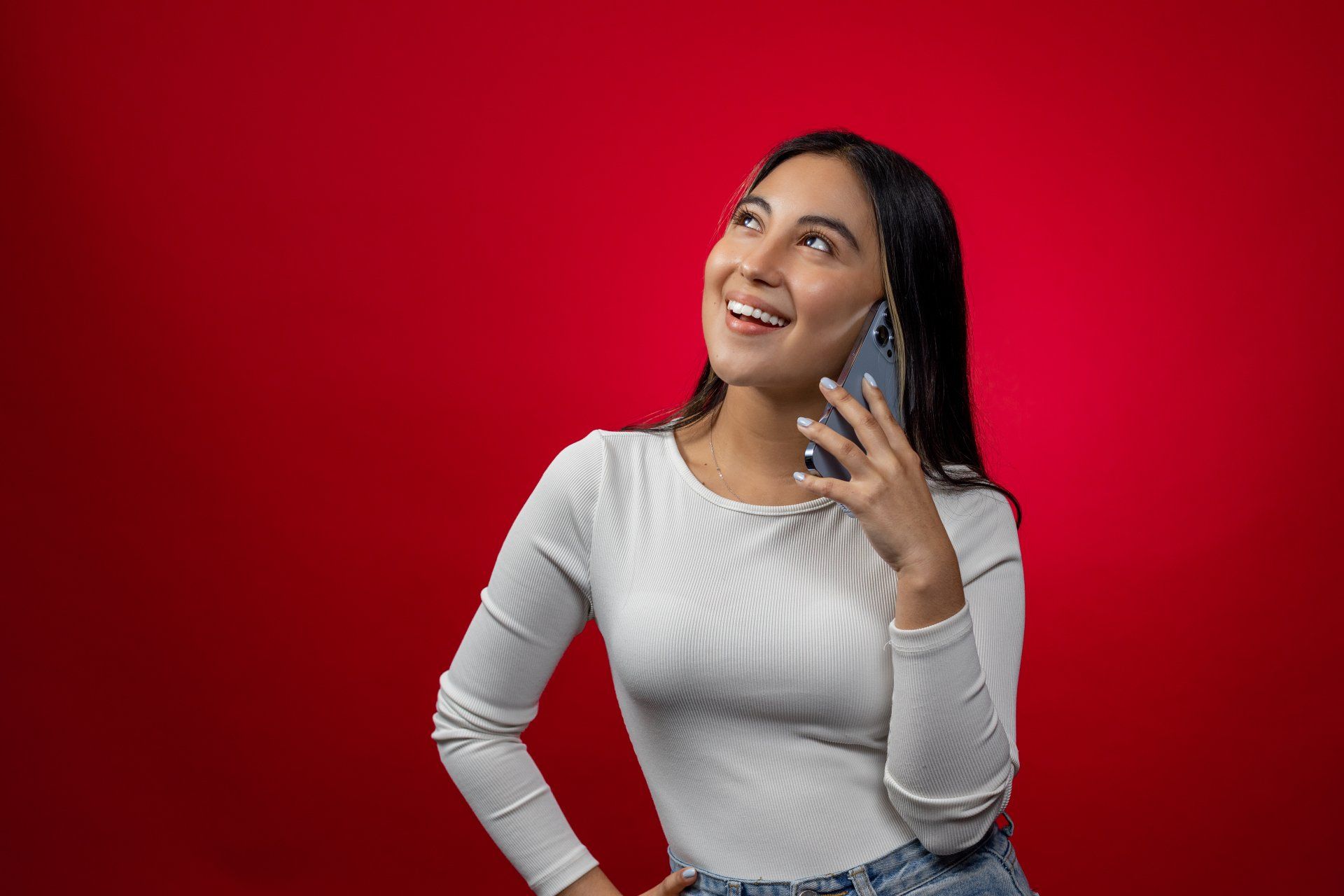a woman is talking on a cell phone in front of a red background .