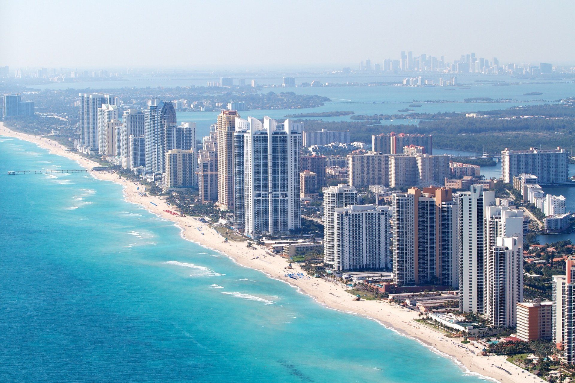 an aerial view of a city along the ocean with lots of tall buildings .