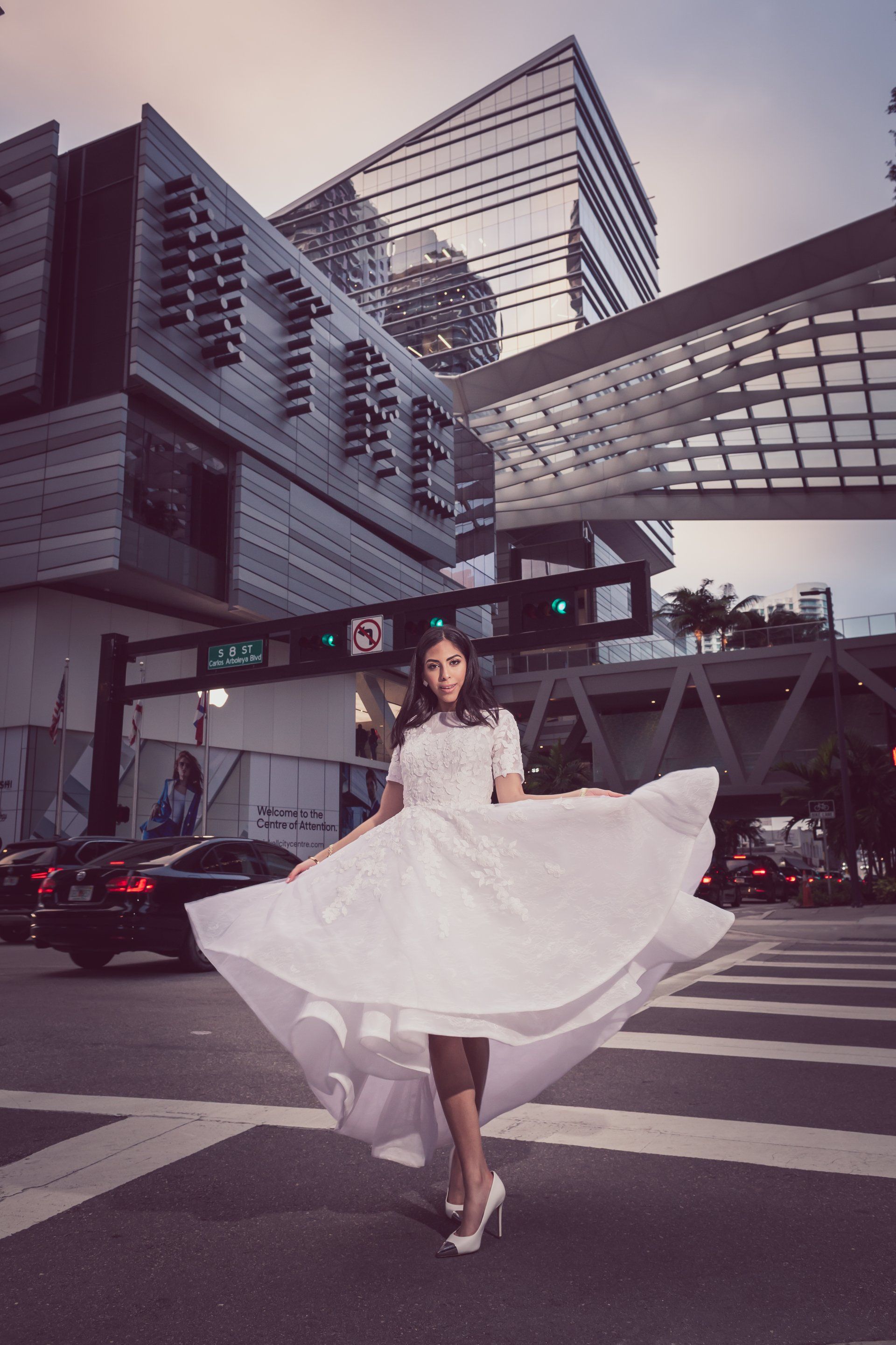 a woman in a white dress is standing in the middle of a city street .